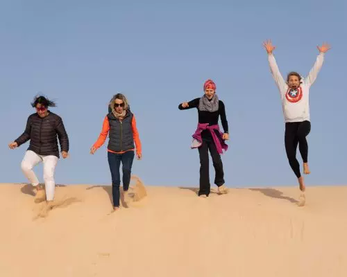Women jumping from a dune